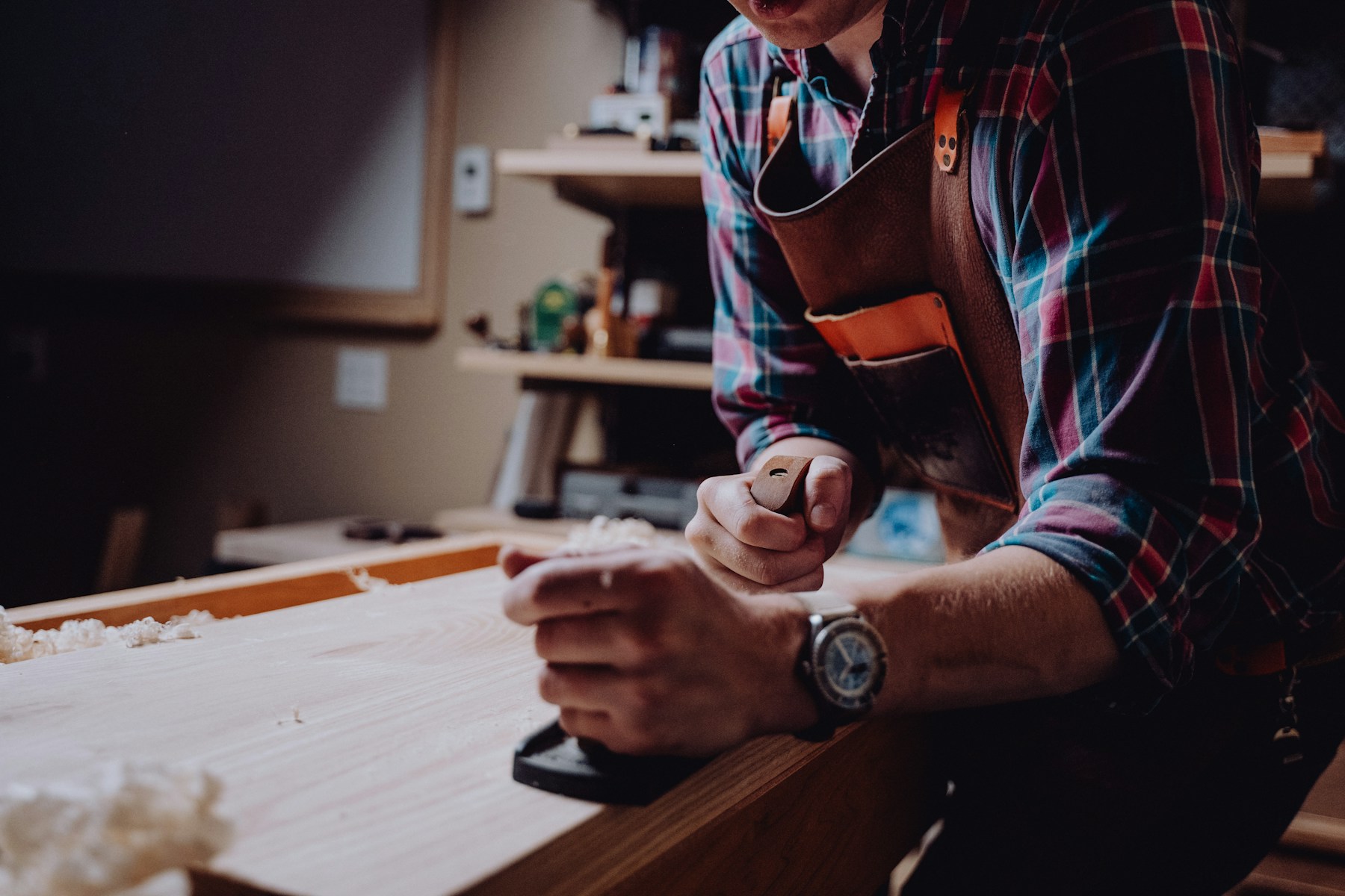 A craftsperson planing wood in a workshop